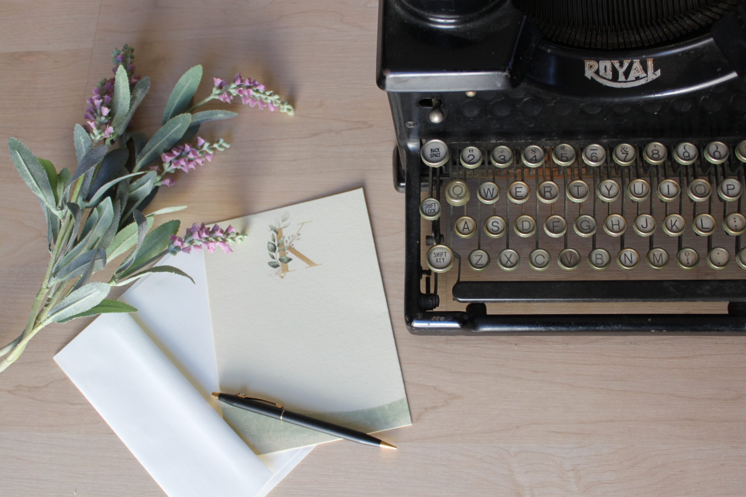 write-for-us Typewriter with flowers, paper and pencil on a wooden desk.